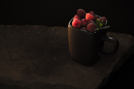 Mug filled with red, ripe raspberries.の写真素材