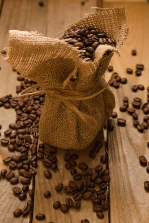 Roasted black coffee beans, spilled from a jute bag into raw planks.の写真素材