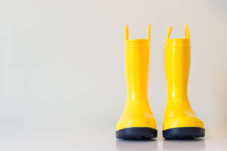 Yellow childrenâs rain boots on white surface.の写真素材