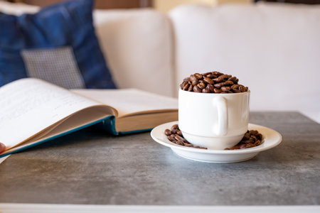 Cup of coffee on grey living room table with book and couch in the backgroundの写真素材