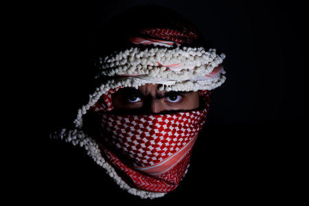 portrait of pearson wearing red keffiyeh on dark background with anger expression on his eyes due to violence and against occupationの写真素材