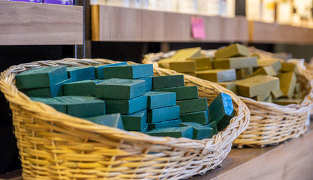 handmade basket full of handmade green soap in a store consist of body care products with wooden backgroundの写真素材