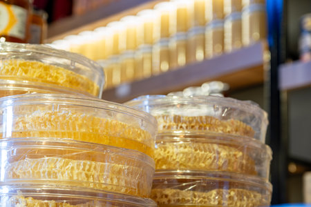 honey with beeswax in round plastic box with background of store shelf full honey jarsの写真素材