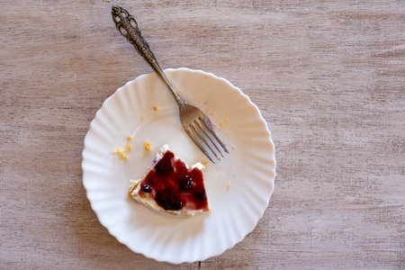 Cold cheesecake with cherry jelly served on wooden table with forks flowers roses and green veilの写真素材