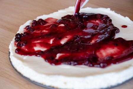 preparing cheesecake with red syrup of red berries and strawberries with cheesecake panの写真素材