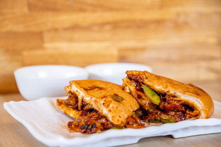 Italian pieces of shawarma full of peppers and BBQ sauces with chicken on wooden table with dipsの写真素材