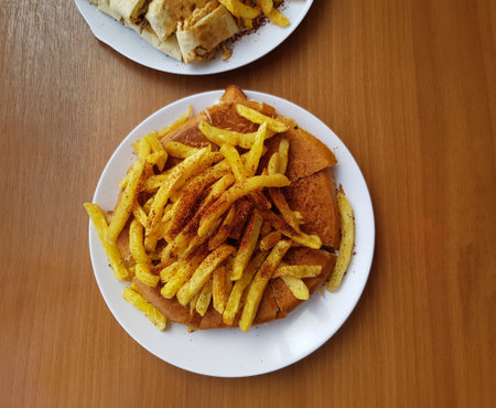 Shawarma dish served on wooden table with close up and top view also with frensh fries on top of the...