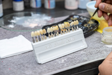 male checking A-D shade guide for tooth crowns to select the proper tooth color in technician lab