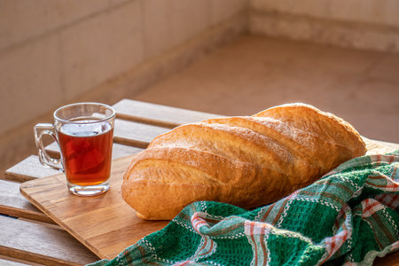 Bread on wooden table ready to be served and cup of tea on white backgroundの写真素材