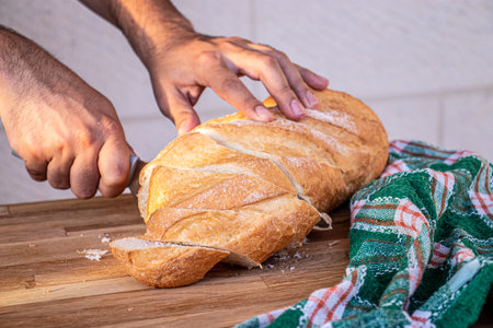 hands holding the knife and cutting the bread into slices to be served