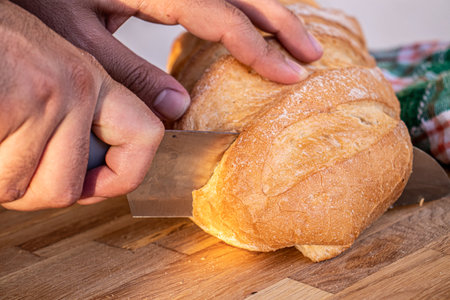 hands holding the knife and cutting the bread into slices to be served