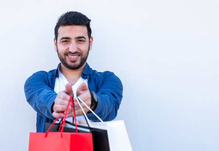 Young male holding shopping bags on white isolated background for black and white friday promotions...