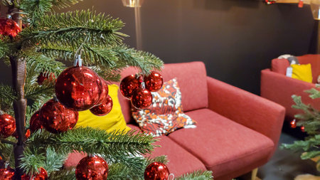 Christmas tree with red decorations in living room with cozy sofa and cushionsの写真素材