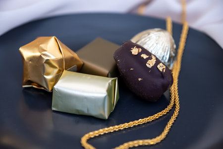 Black bowl full of chocolate wrapped with golden paper