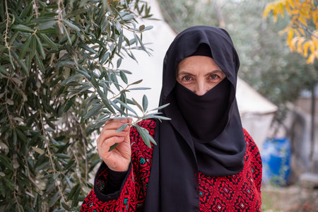 Portrait for woman wearing traditional clothes in refugee camp behinde olive treeの写真素材