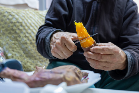 Old man eating sweet potatoの写真素材