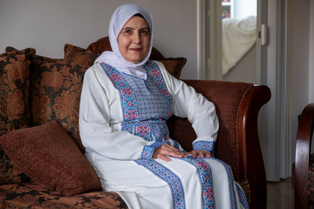 old lady wearing traditional clothes sitting on couch with smile on her faceの写真素材