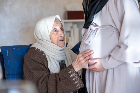 muslim old woman feeling excited for her new grandson touch her daughter tummy to feel fetus movementsの写真素材