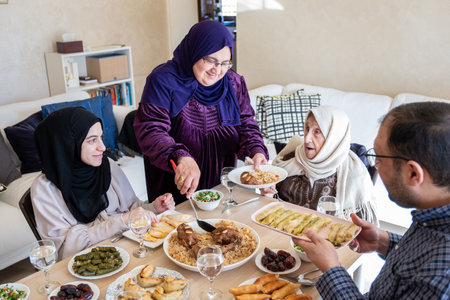 Arabian family having dinner together on wooden table with father,mother,grandfather,grandmother and...