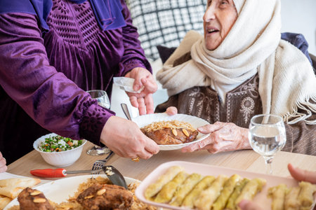 Arabian family having dinner together on wooden table with father,mother,grandfather,grandmother and sonの写真素材