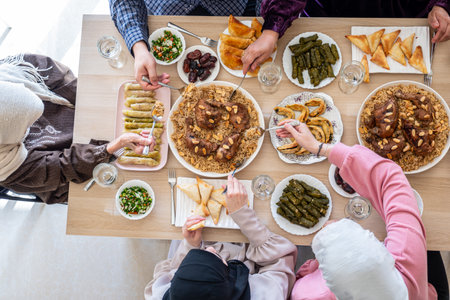 Top view for Arabian family having dinner together on wooden table with father,mother,grandfather,grandmother and sonの写真素材