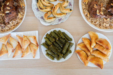Dish of grape rolls on wooden table from top view with sambousek and qatayef
