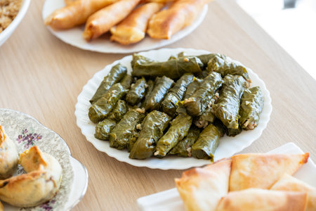 Dish of grape rolls on wooden table from top view with sambousek and qatayefの写真素材