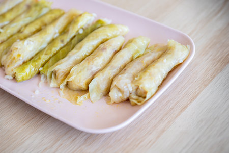 dish of Stuffed Cabbage Rolls on wooden table and pink dish, traditional jordanian recipe