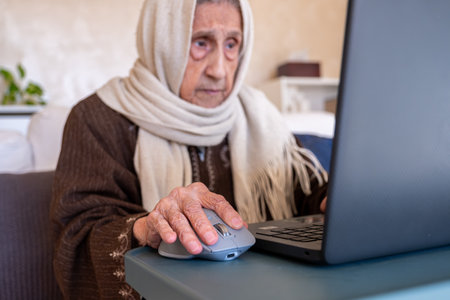 old lady using laptop in modern living room for online purposesの写真素材