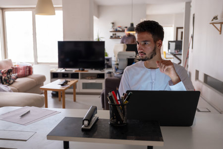 Young Man Working From Home At Modern Office Desk With Laptop And Office Suppliesの写真素材
