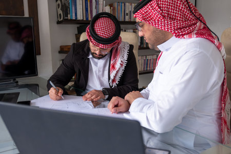 arabic males working on project using laptop and papers while talking and checking all possibilities...