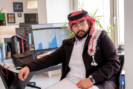 portrait for arabic male on his chair in office with smile on his faceの写真素材