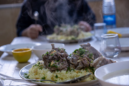 hot fresh mansaf steam with hands around it ready to be eaten on family table for iftarの写真素材