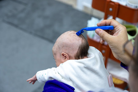 baby girl having her hair shaved with a razor.の写真素材