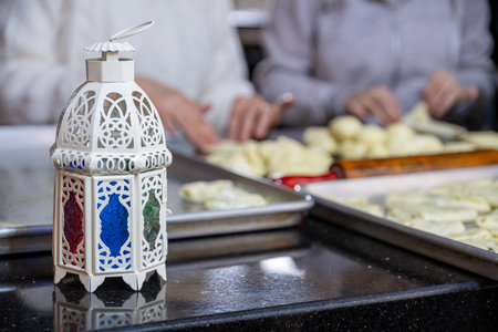 mother and daughter are working together preparing pastries for iftar in ramadan with lantern in frontの写真素材