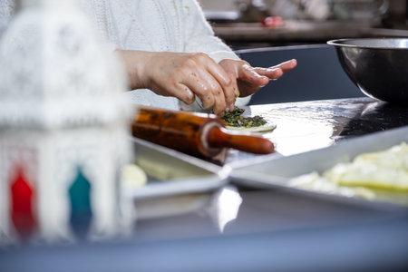 preparing arabic traditional pastries by female hands stuffing them with spinach and red chiliの写真素材