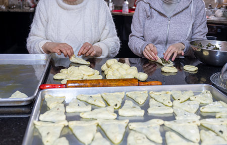 preparing arabic traditional pastries by female hands stuffing them with spinach and red chiliの写真素材