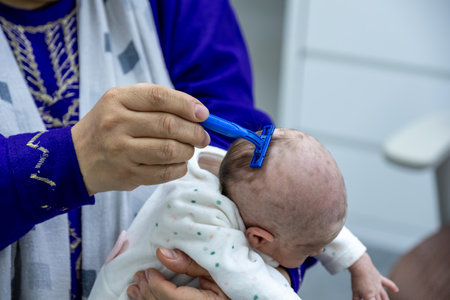 baby girl getting her hair shaved with a razor. shaving hair for 1 monthの写真素材