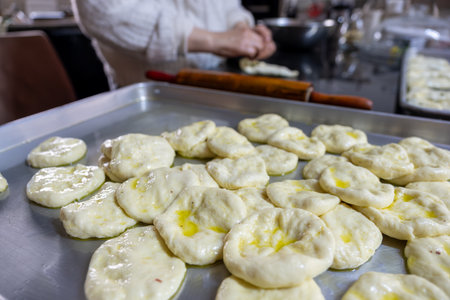 old woman hands using rolling pin to flatten the dough  on black marble  covered with oil