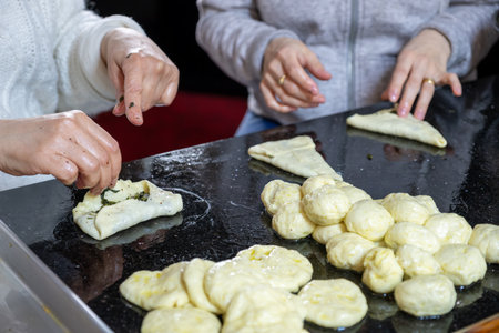 preparing arabic traditional pastries by female hands stuffing them with spinach and red chiliの写真素材