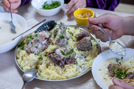 male hands with mansaf from a point of view while preparing his plate with meat,rice jameed ,nuts and parsley during iftar in ramadanの写真素材
