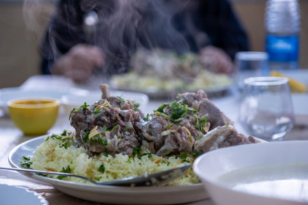 hot fresh mansaf steam with hands around it ready to be eaten on family table for iftarの写真素材