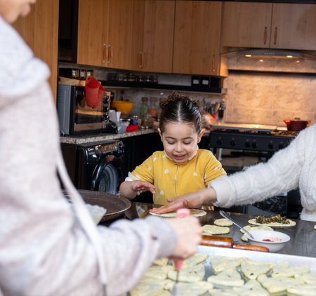 Cheerful kid helping mother in preparing pastries in kitchen , preparing food togetherの写真素材