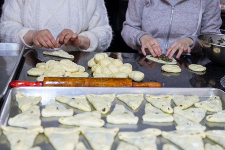 preparing traditional pastries by female hands stuffing them with spinach and red chiliの写真素材
