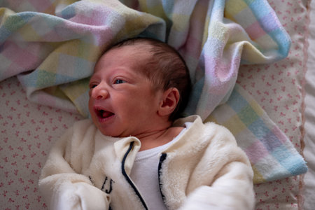 mother changing pampers for her baby , holding his tiny leg while closing trousersの写真素材