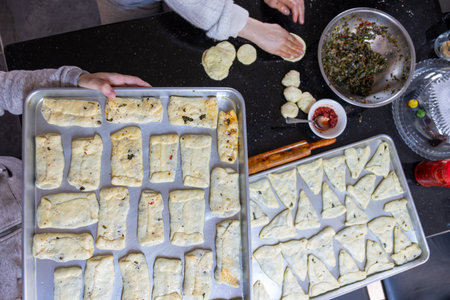 preparing arabic traditional pastries by female hands stuffing them with spinach and red chiliの写真素材