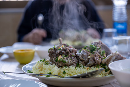 male hands with mansaf from a point of view while preparing his plate with meat,rice jameed ,nuts and parsley during iftar in ramadanの写真素材