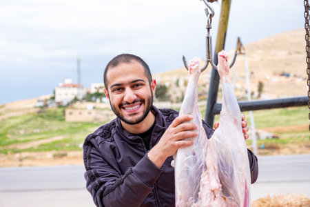 A man is posing for a portrait with his Eid sheep, a smile on his face, celebrating Eidの写真素材