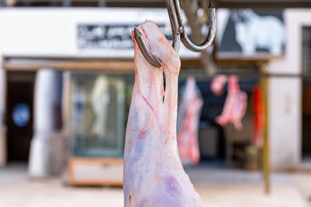 A man is butchering a sheep that is hanging on a hook, carefully preparing it for consumption