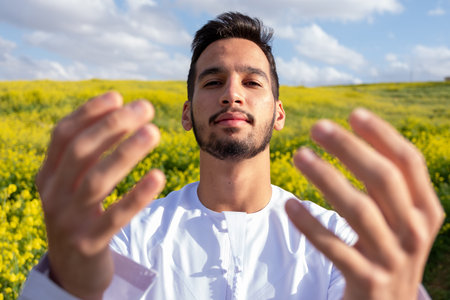 An Arab people enjoys a spring picnic in a meadow near Abu Dhabi. Seated on chairs, they savor cups of coffee under a blue sky with scattered cloudsの写真素材